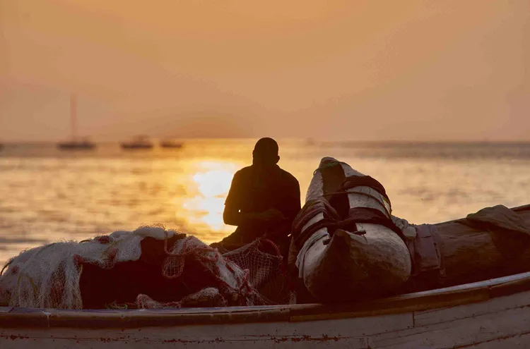 A fisherman mends his nets as the sun sets over the lake. Photo: Nkwazi Magazine/Chosa Mweemba.