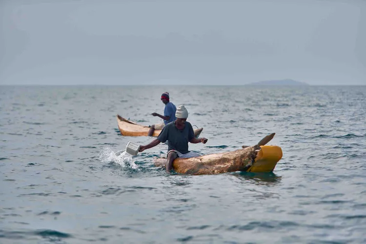 A fisherman bails water out of his dugout as the clouds gather above. Photo: Nkwazi Magazine/Chosa Mweemba.