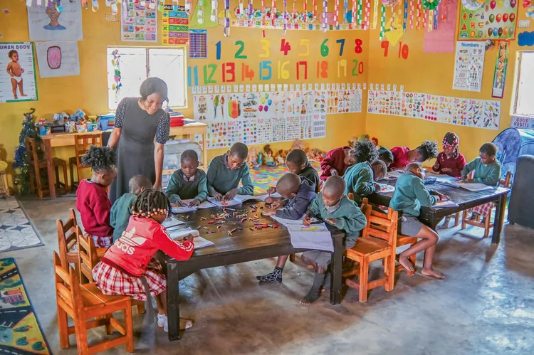 A teacher assists children in a classroom at Footprints of Hope, a safe haven for rescued children. (Image courtesy of Bich'ri Photography).