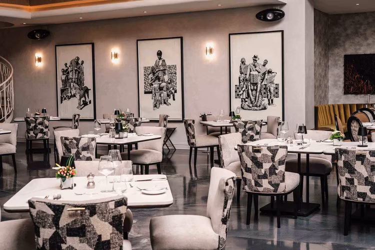 The restaurant's décor is beautifully understated, with vibrant wall art complementing the room's wood accents. (Image courtesy of The Saxon Hotel, Villas, Spa).