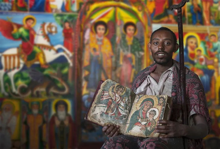 An Ethiopian Orthodox Priest holding up an ancient text.
